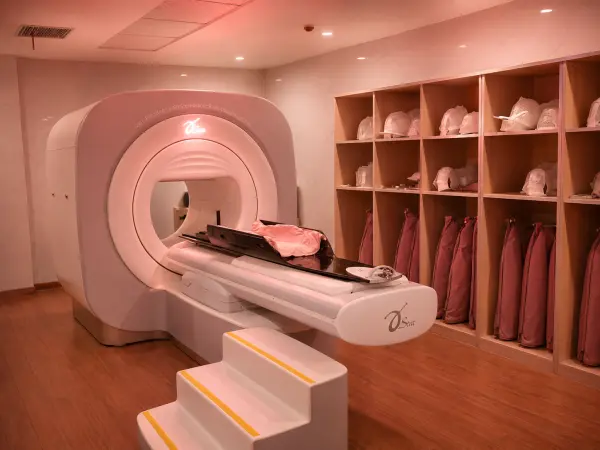 MRI scanner in a clinic room with the patient table extended, coats stored in cubbies along the wall.