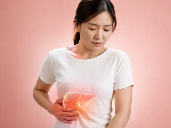 Woman in a white T-shirt clutching her stomach and wincing in pain, suggesting abdominal discomfort on camera.